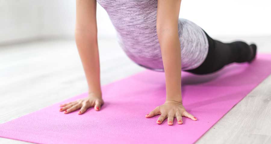Woman doing yoga on a pink mat