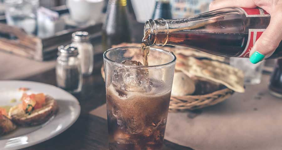 Pouring in carbonated drink into glass