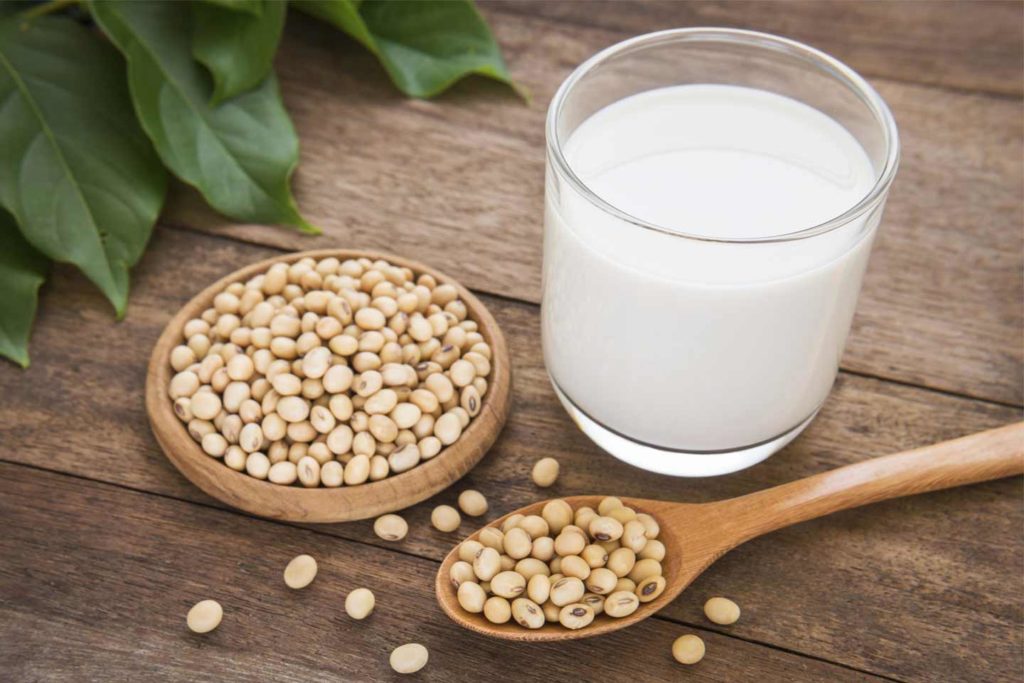 A glass of soy milk and soy beans on a wooden table