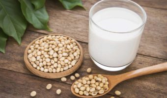 A glass of soy milk and soy beans on a wooden table