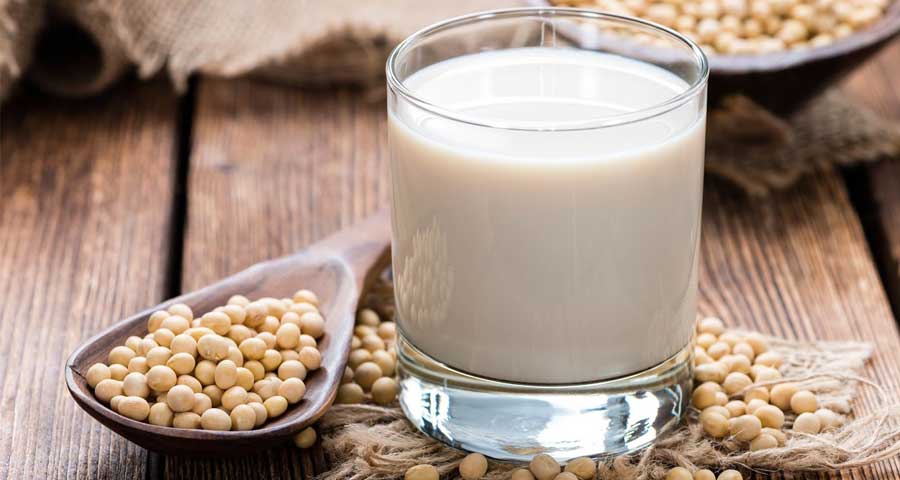 Soy Milk next to a spoon full of soy beans